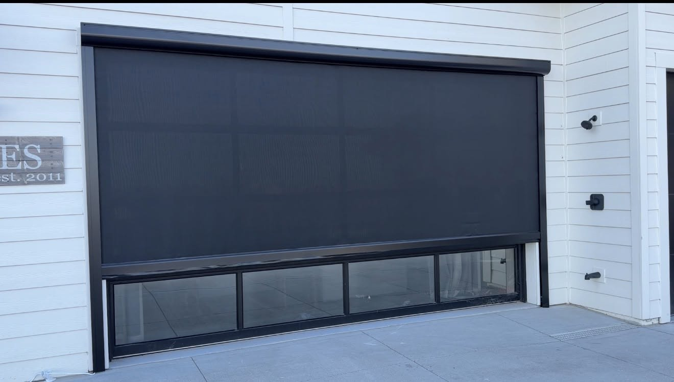 Dark retractable screen lowered over a residential garage door opening