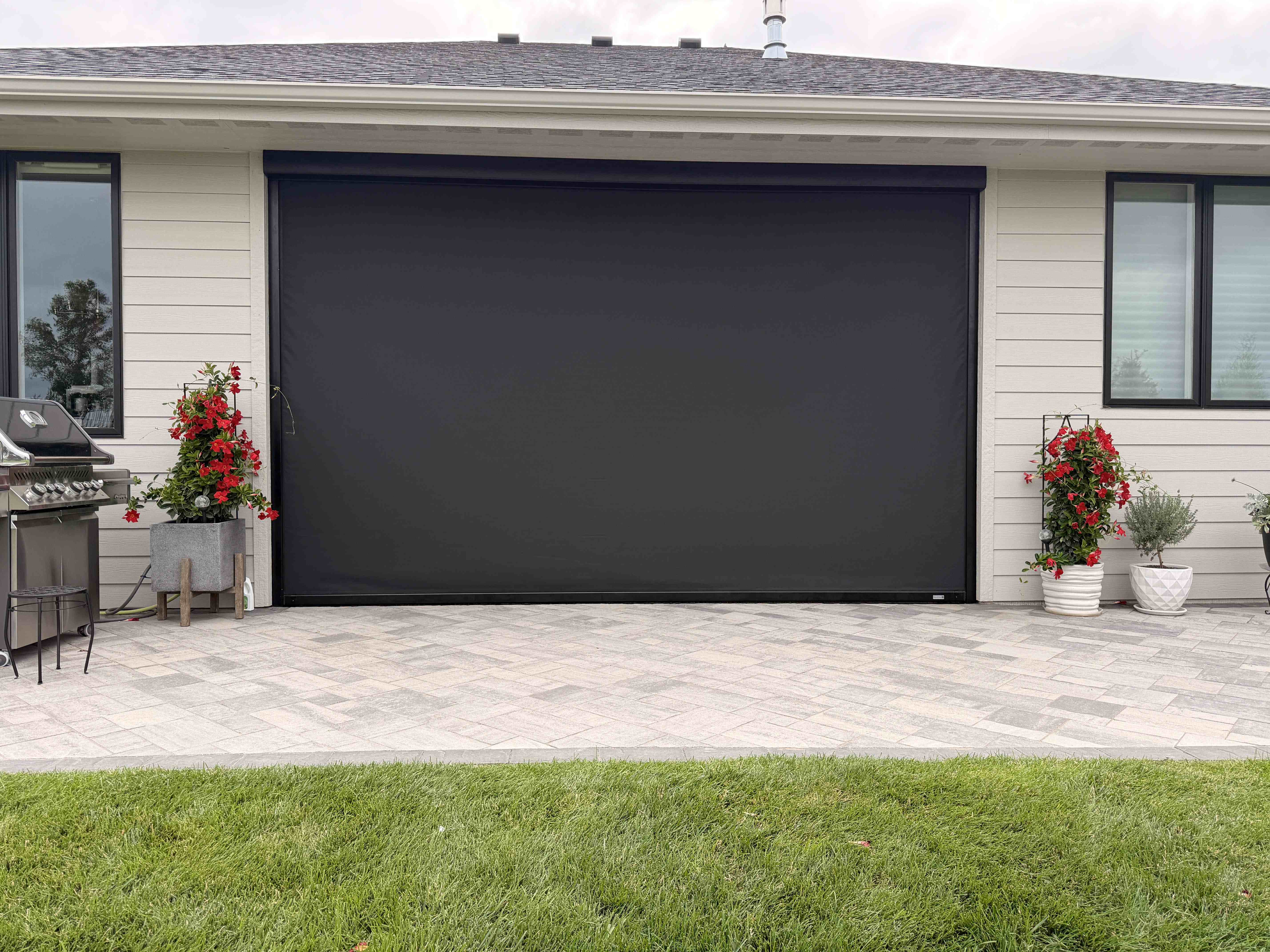 Home patio with a large black motorized privacy screen fully lowered between windows